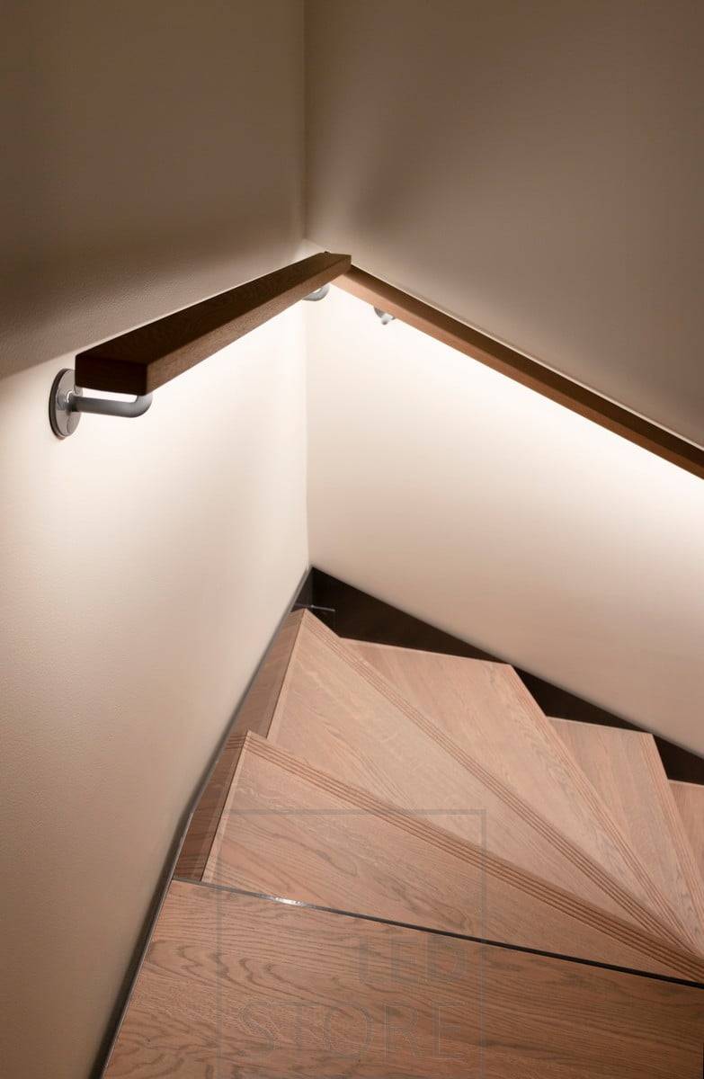 Bande LED sur une rampe éclairant les escaliers d'une lumière indirecte.